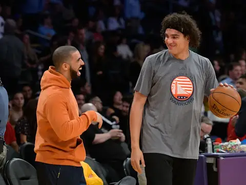 Drake conversa com Anderson Varejão, que segura uma bola e veste roupa dos Warriors.